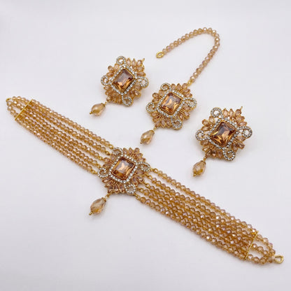 Gold jewelry set with choker, earrings, and tikka on a white background