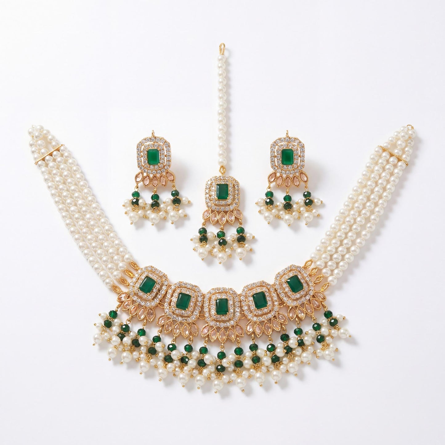 pakistani jewelry set with pearls, gold, and green gemstones on a white background