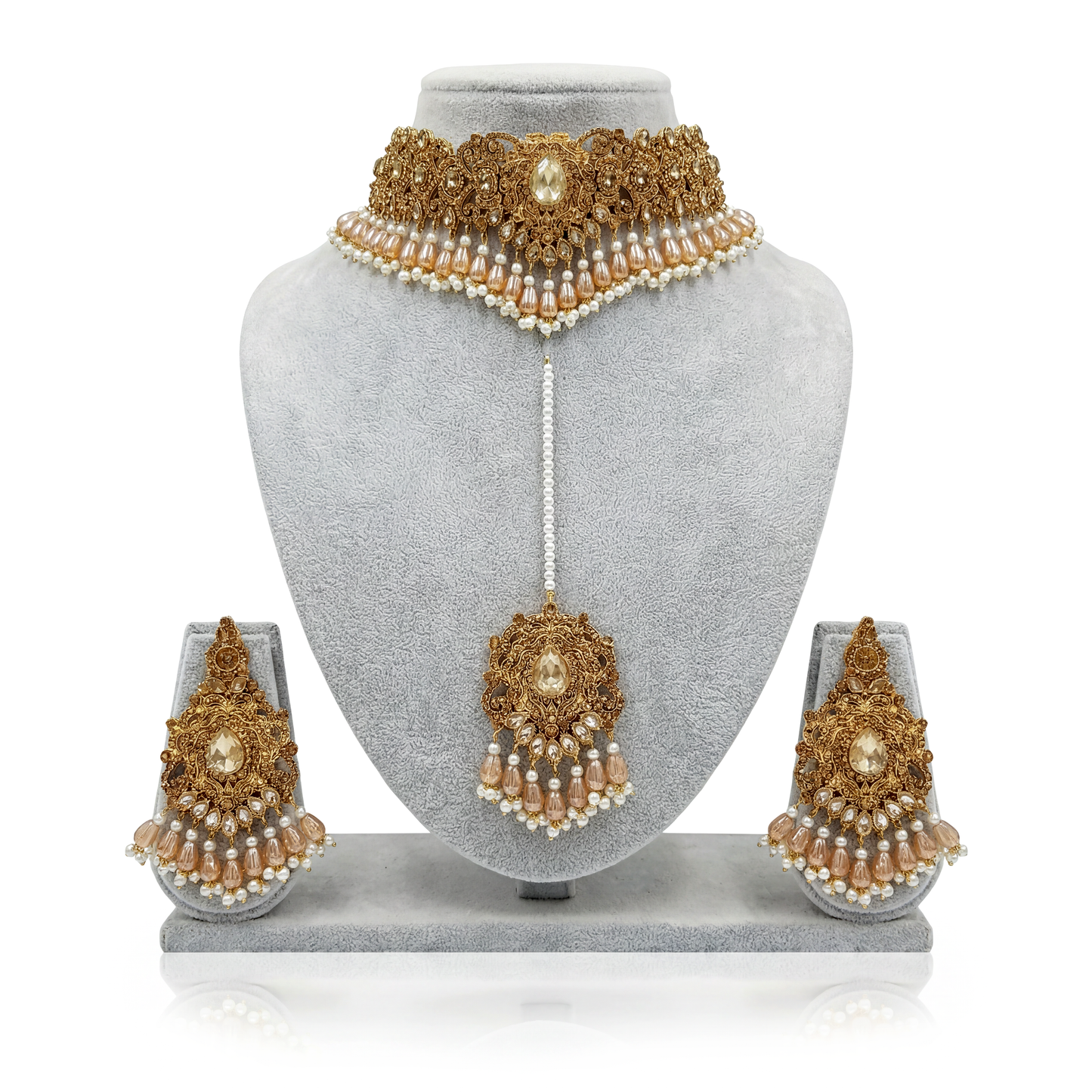 pakistani gold and pearl bridal jewelry set on a gray mannequin bust with earrings displayed below.