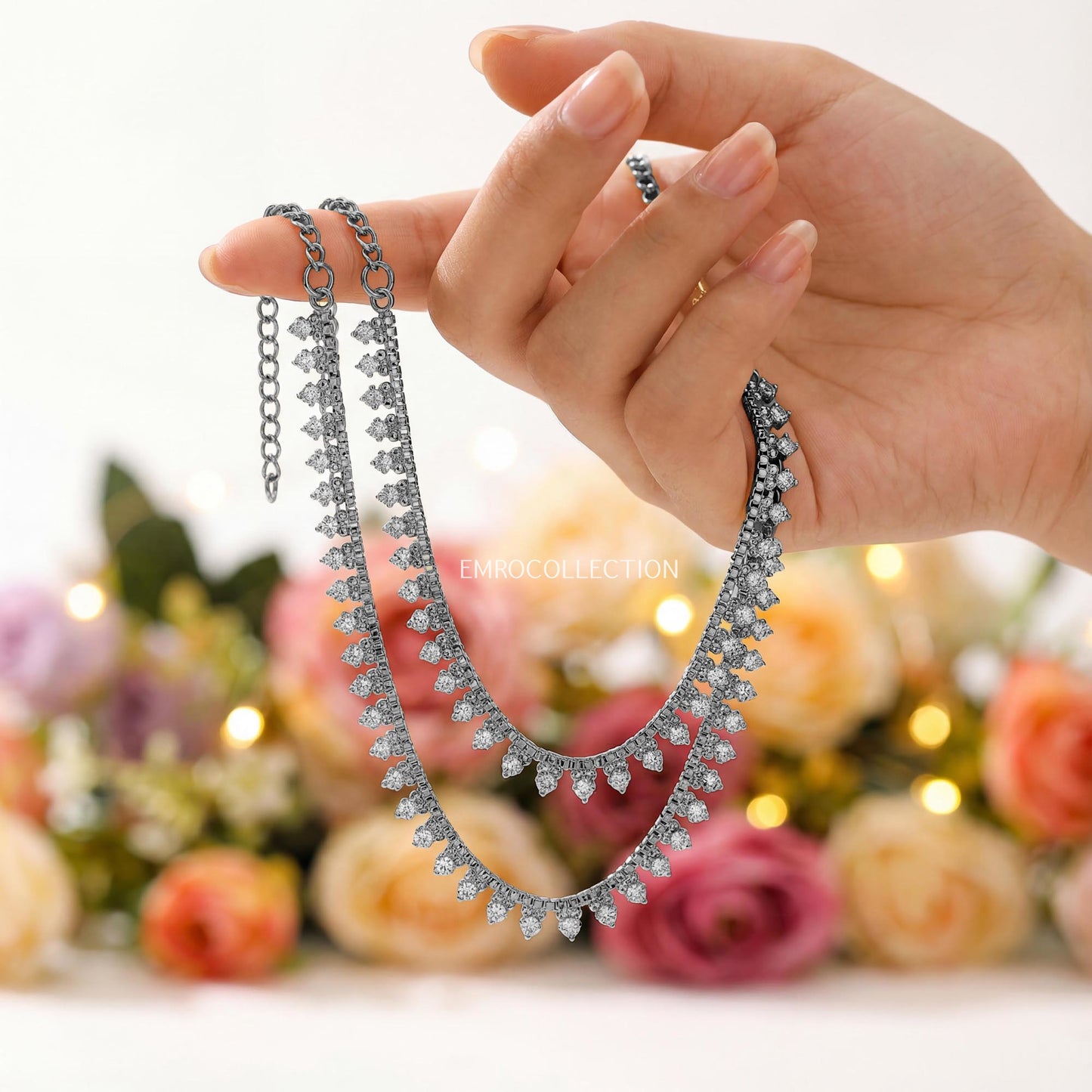 hand holding a silver anklets with a floral background - trending pakistani jewellery