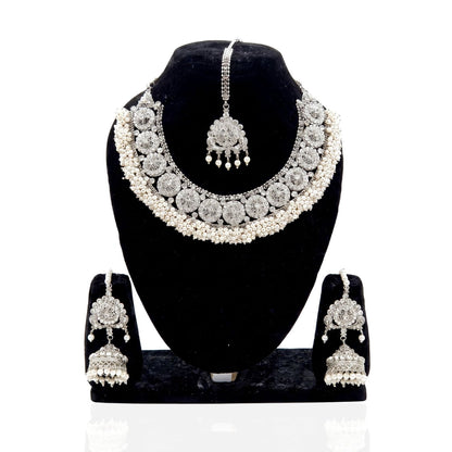 A silver-toned traditional Indian jewelry set displayed on a black velvet mannequin bust, including a choker necklace, matching maang tikka, and jhumka earrings.