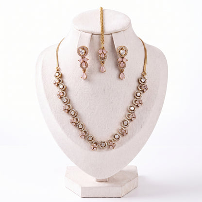 The Simple Gold and Baby Pink Necklace, Earrings and Tikka Set laid out on a plain backdrop
