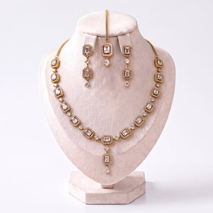 The Simple Gold and White Necklace, Earrings and Tikka Set arranged together on a plain backdrop