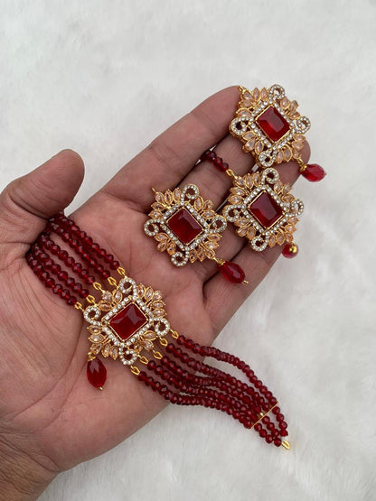 Gold and Maroon jewelry set on a hand with a white background pakistani jewellery