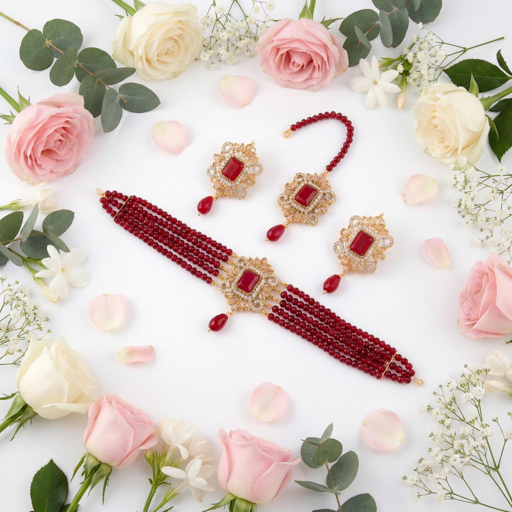 Jewelry set with Maroon beads and gold accents on a white background with flowers Pakistani jewellery