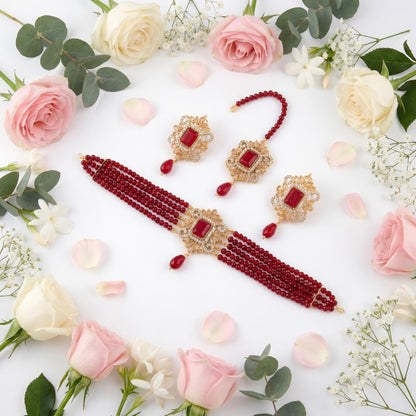 Jewelry set with Maroon beads and gold accents on a white background with flowers Pakistani jewellery