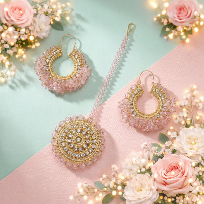 Gold and pink earrings on a pink surface with flowers and lights