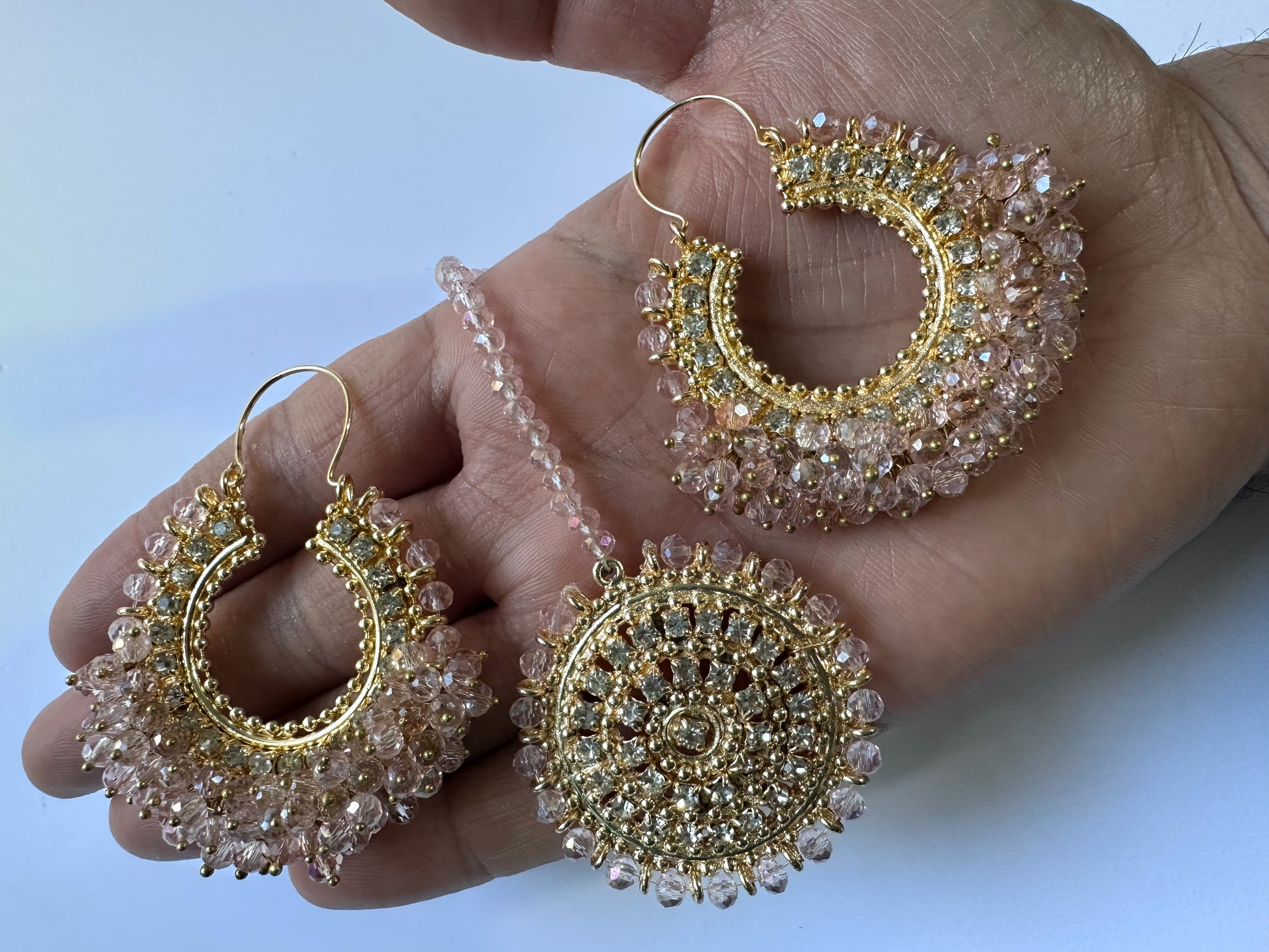 Goldand pink hoop earrings with gemstones held in a hand - trending Pakistani jewellery