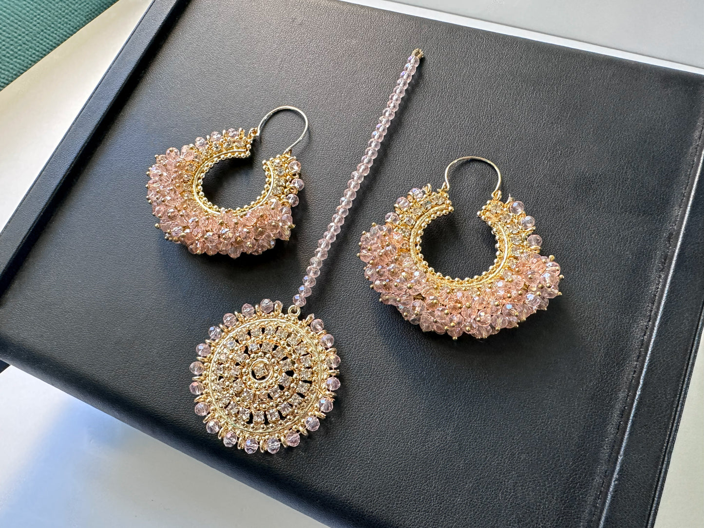 baby pink chand bali earrings tikka against a black display. trending pakistani earrings tikka