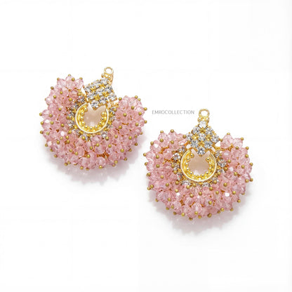 Pair of baby pink beaded earrings with gold accents on a white background