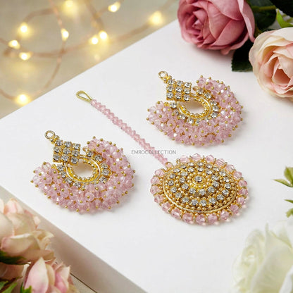 trending pakistani earrings tikka on a white surface with flowers and lights.
