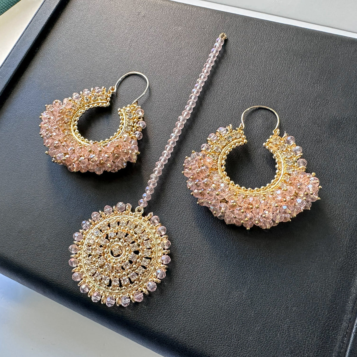 baby pink chand bali earrings tikka against a black display. trending pakistani earrings tikka