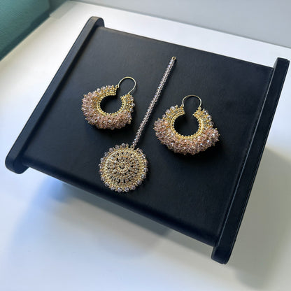 top view of baby pink chand bali earrings tikka against a black display. Trending pakistani jewellery