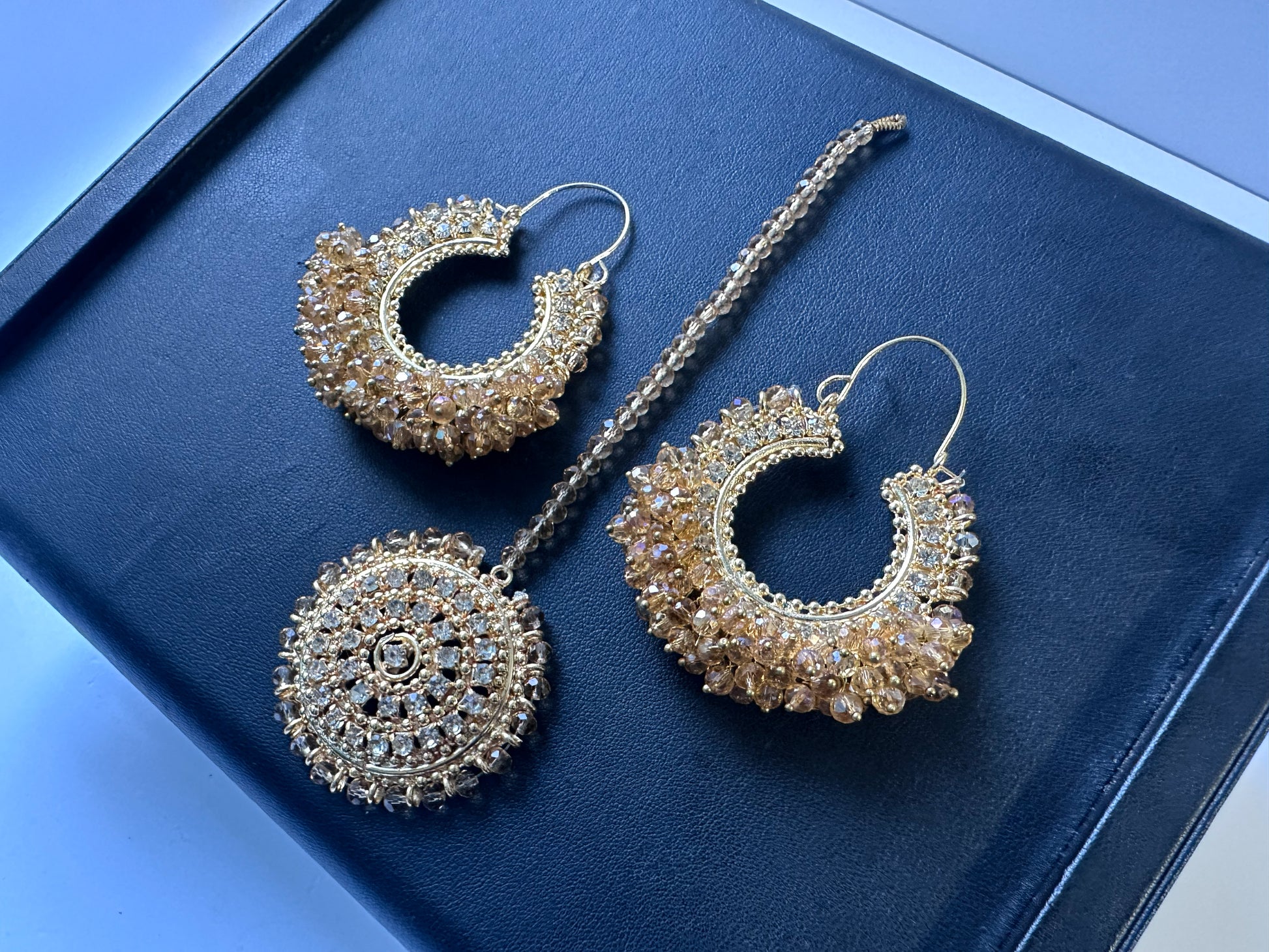 Gold hoop earrings and maang tikka on a black display. side angle. Trending pakistani jewellery
