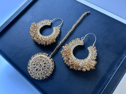 Gold hoop earrings and maang tikka on a black display. side angle. Trending pakistani jewellery