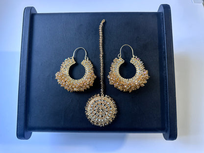 Gold hoop earrings and maang tikka on a black display. Trending pakistani jewellery