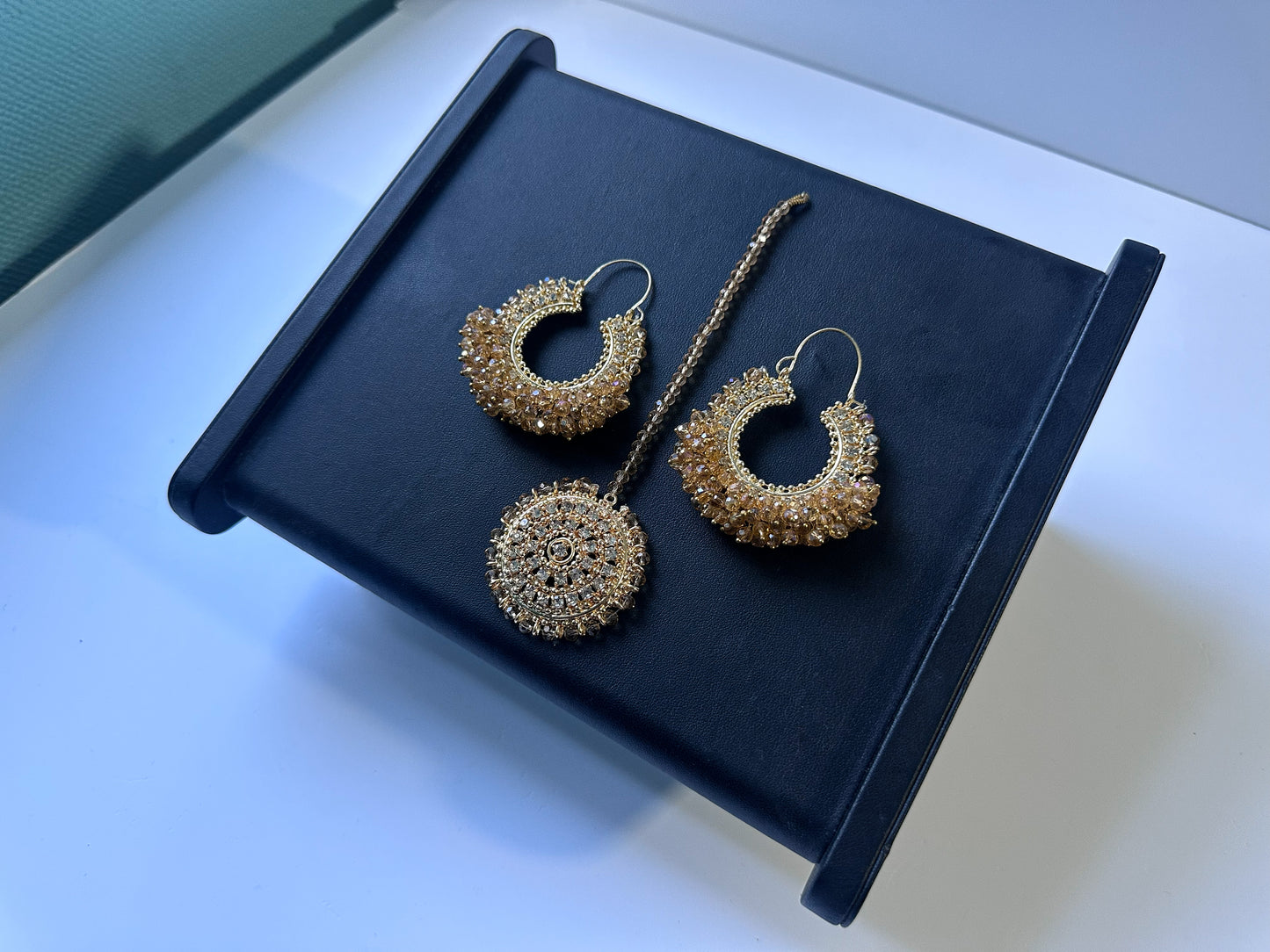 gold hoop earrings and tikka on a black stand- trending pakistani earrings tikka