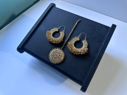Gold hoop earrings and tikka on a black stand- Trending pakistani earrings tikka