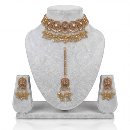Simple golden choker set with earrings and maang tikka displayed on a light grey velvet dummy – pakistani jewellery
