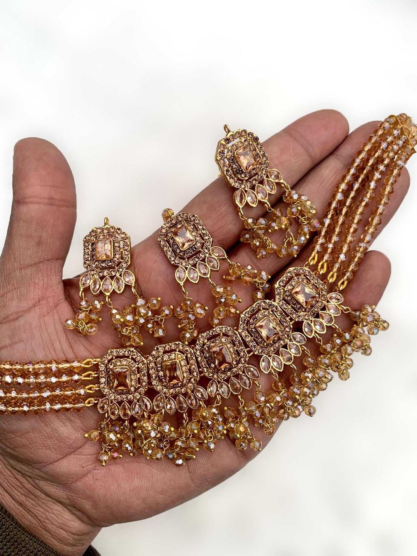 hand holding simple golden choker set with earrings and maang tikka for detailed view – pakistani jewellery