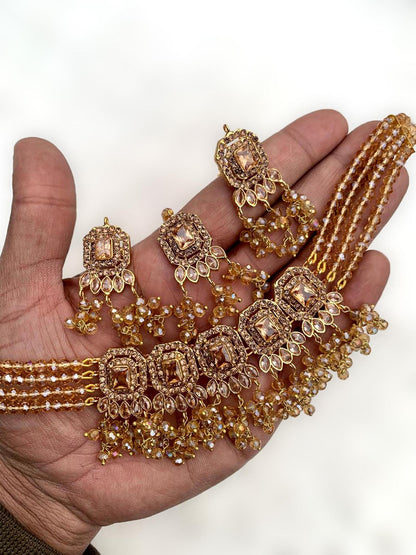 Hand holding simple golden choker set with earrings and maang tikka for detailed view – pakistani jewellery