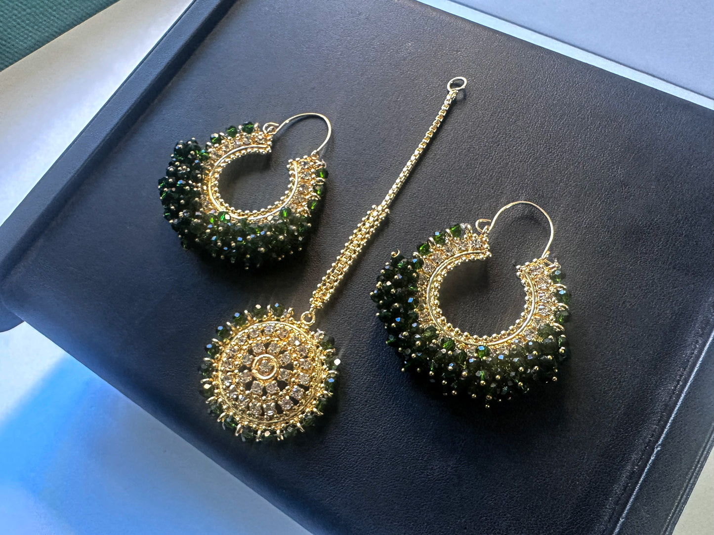 green earrings tikka against a dark display. trending pakistani jewellery