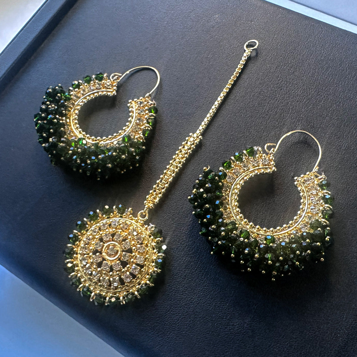 green earrings tikka against a dark display. trending pakistani jewellery