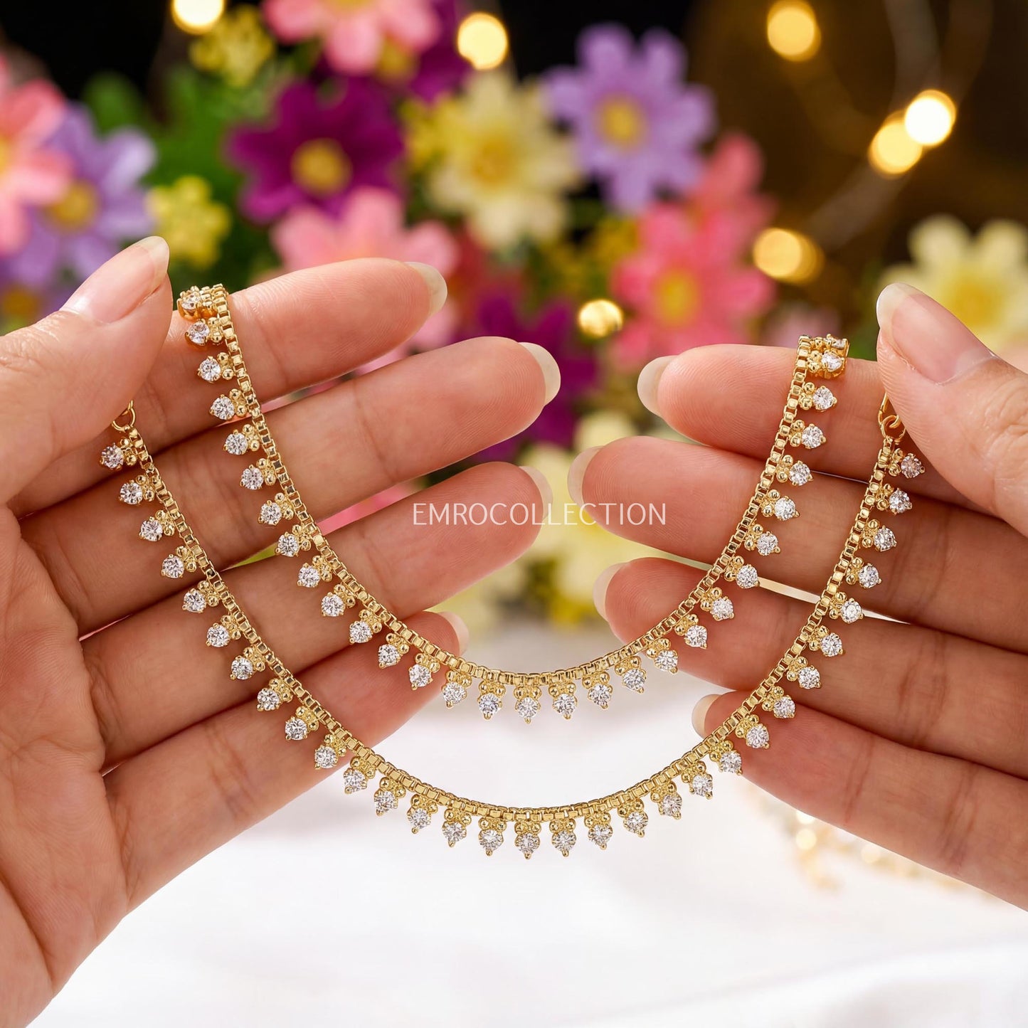 elegant golden payal anklet held by hands with a blurred floral background