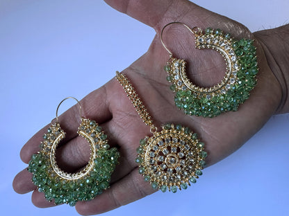 Gold and light green earrings tikka on a hand - Trending pakistani earrings tikka