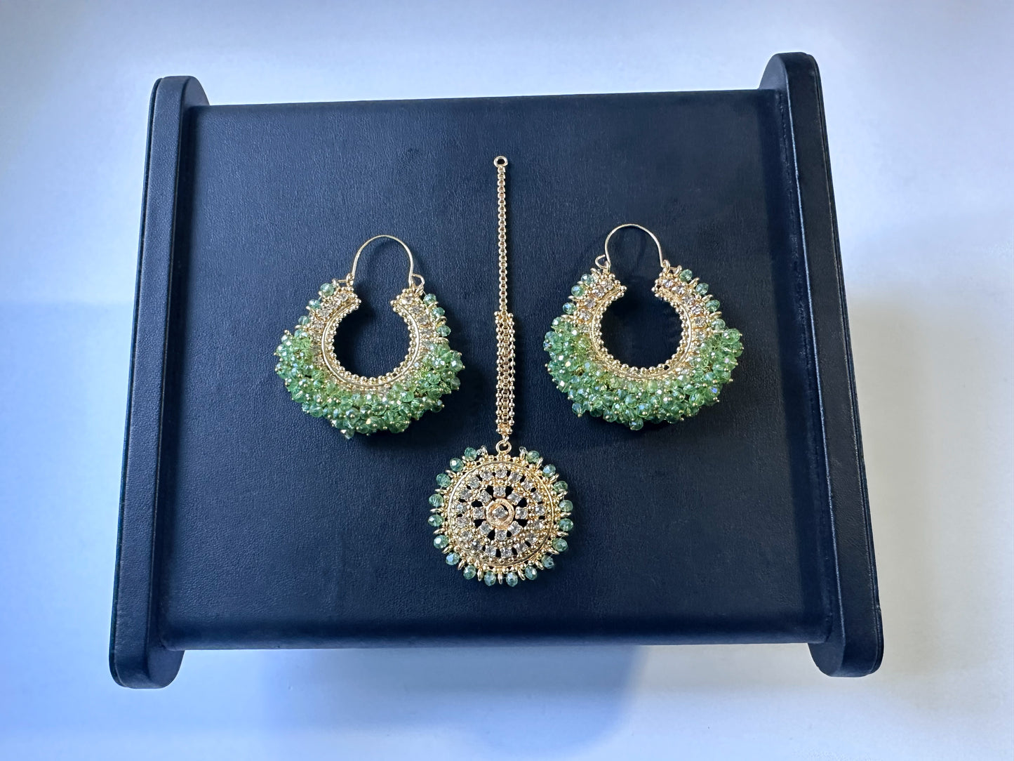 mint green chand bali earrings and maang tikka set on a black display - trending pakistani earrings tikka. 