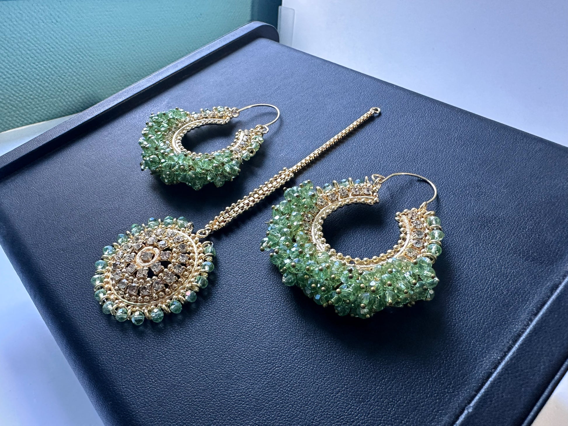 Light green chand bali earrings and maang tikka displayed flat on a dark display. Trending pakistani earrings tikka. 