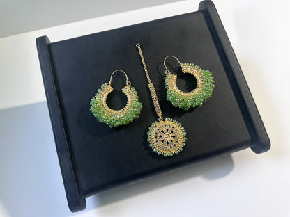 light green chand bali earrings and maang tikka on a black display. 