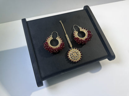 Dark maroon chand bali earrings and maang tikka set against a dark display - Trending pakistani erarrings tikka set