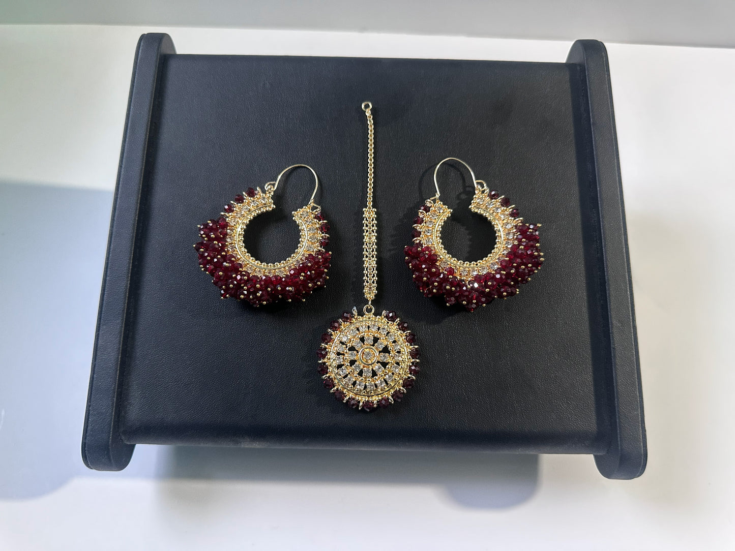 maroon hoop earrings tikka set on a dark display. trending pakistani jewellery