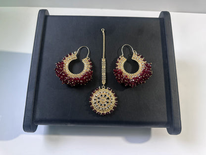 Maroon hoop earrings tikka set on a dark display. Trending Pakistani jewellery