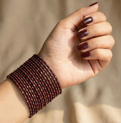 Model wearing maroon bangles with golden dots churi set on wrist showing elegant Indian bridal jewellery styling indian jewellery