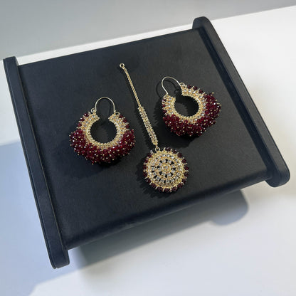 Dark maroon chand bali earrings and maang tikka set against a dark display - Trending pakistani erarrings tikka set
