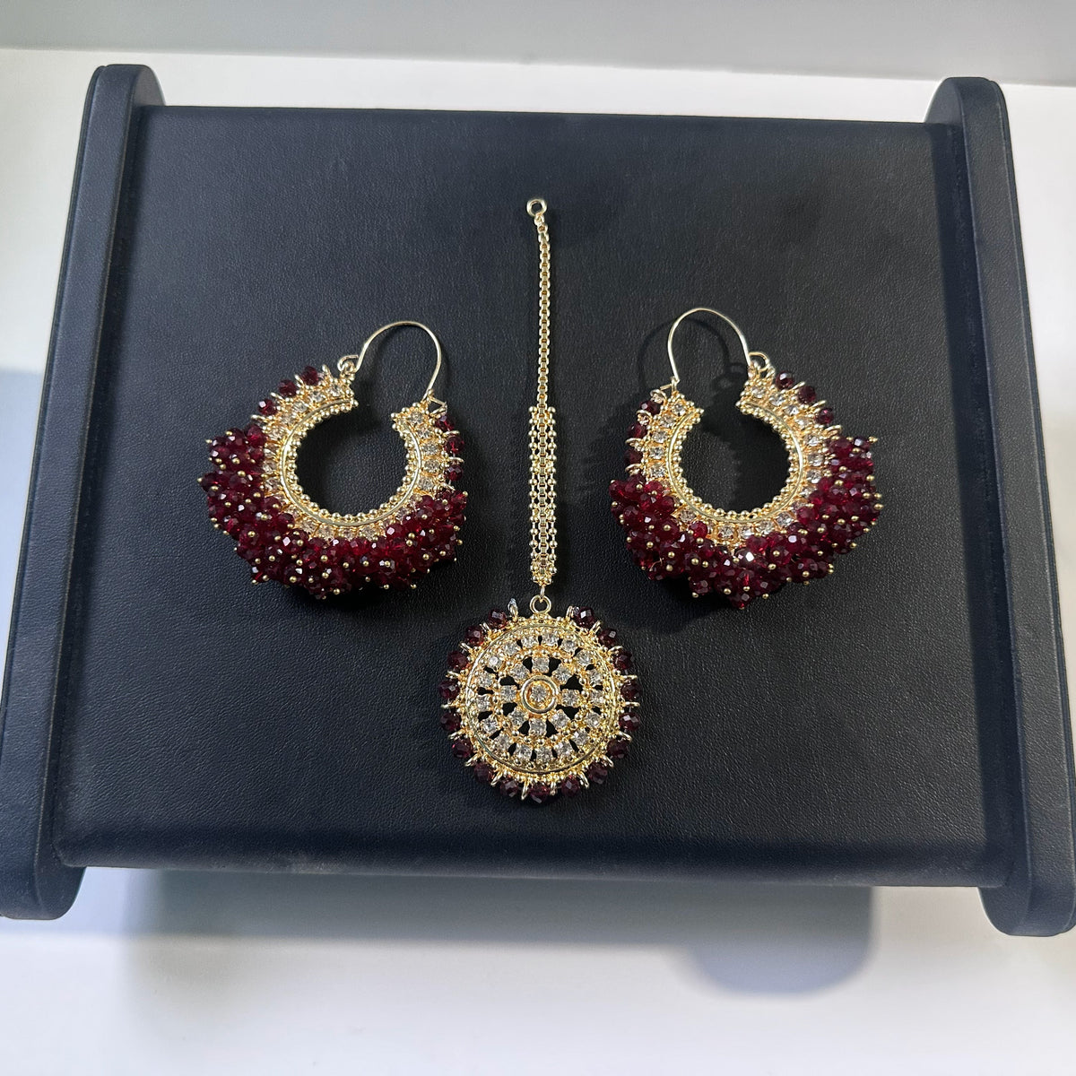 maroon hoop earrings tikka set on a dark display. trending pakistani jewellery