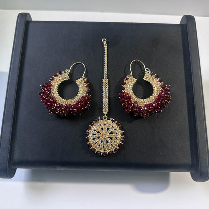 Maroon hoop earrings tikka set on a dark display. Trending Pakistani jewellery