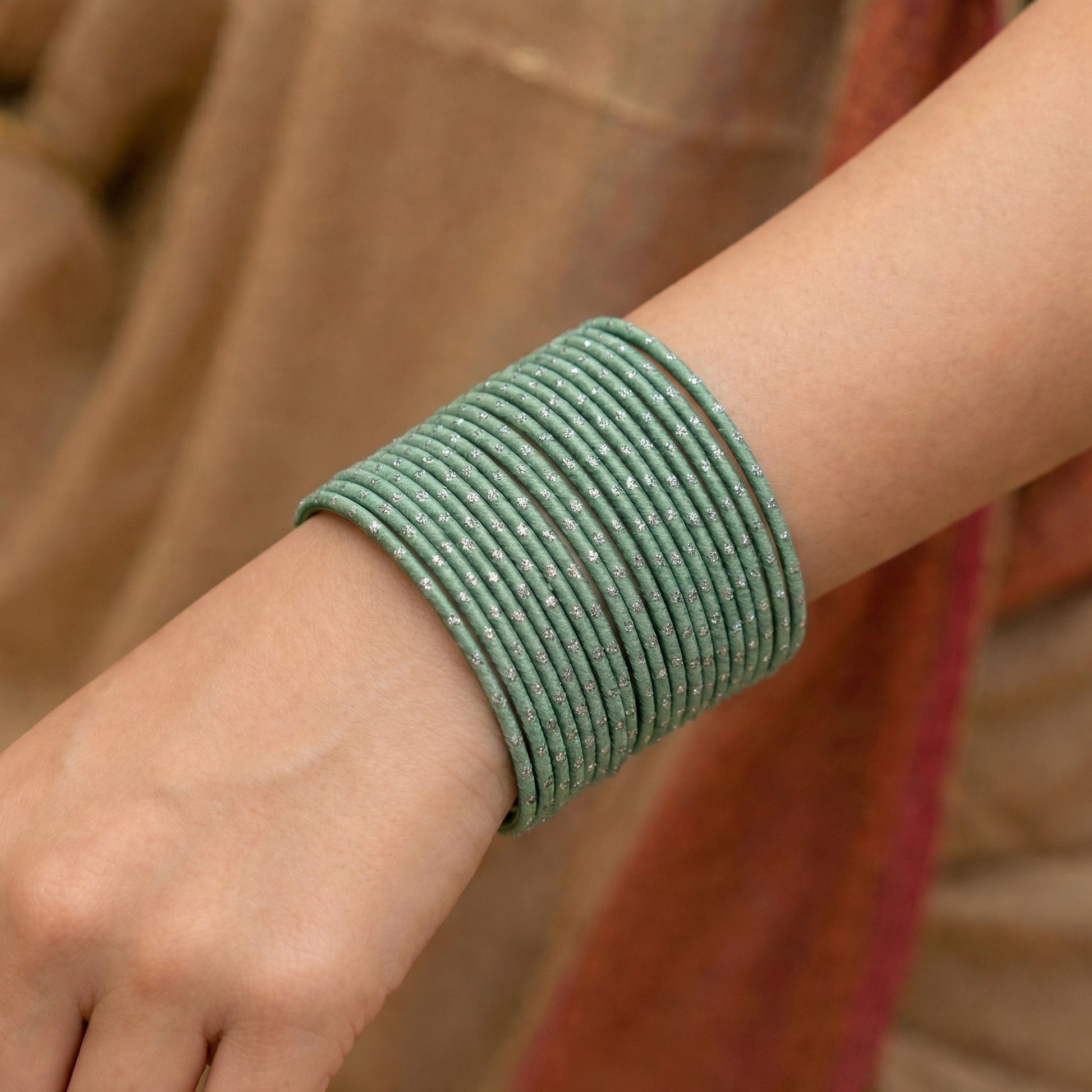 Close-up of model wrist wearing mint green bangles with silver dots showing soft pastel colour and festive Indian jewellery look indian jewellery