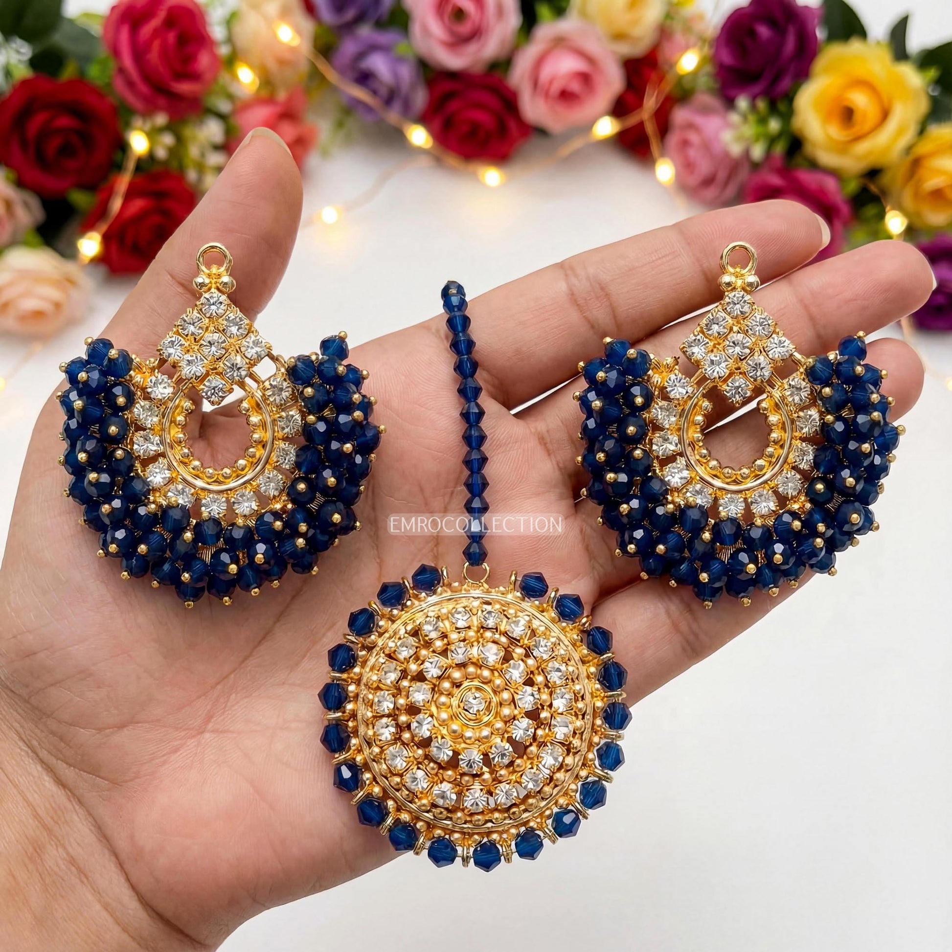 Gold and navy blue earrings tikka set held in a hand - sauitable for weddings and parties