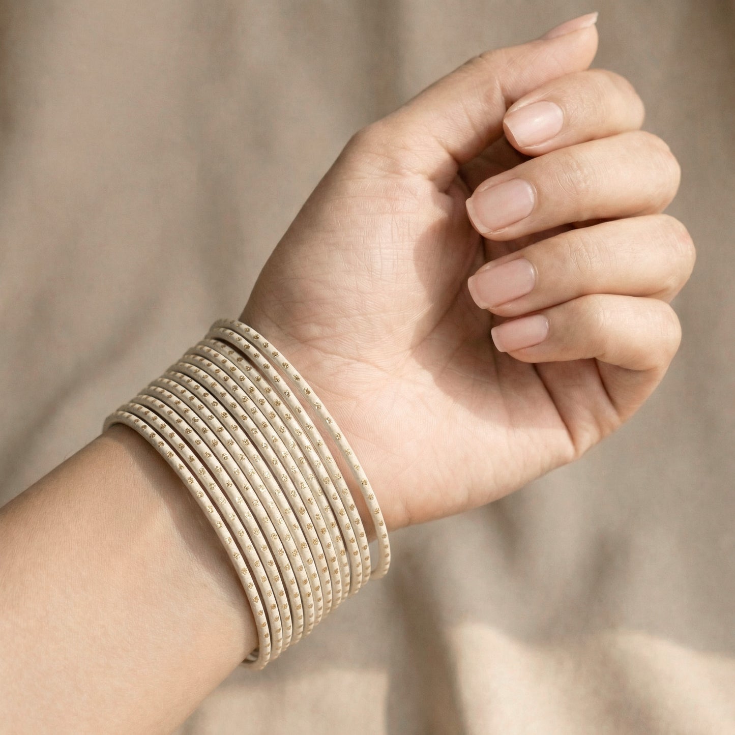 model wearing off-white bangles with golden dots on wrist showing full stack of 24 slim bangles in elegant pakistani bridal style indian jewellery