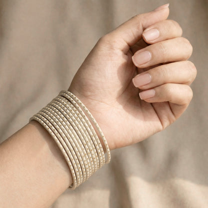 Model wearing off-white bangles with golden dots on wrist showing full stack of 24 slim bangles in elegant Pakistani bridal style indian jewellery