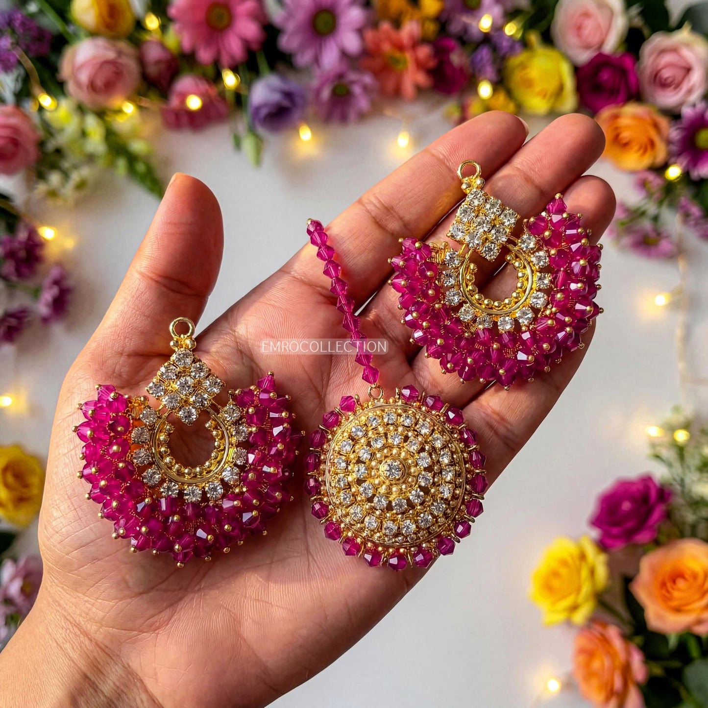 hand holding pink and gold earrings tikka with a floral background - trending pakistani earrings tikka