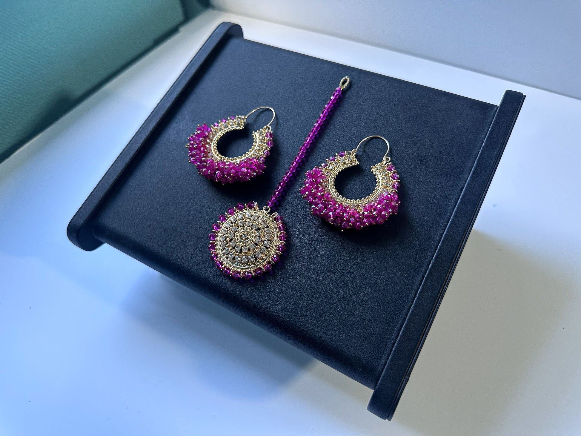 Pakistani trending shocking pink Chand Bali earrings tikka on a black display. 