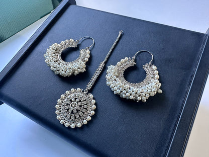Traditional silver white Chand Bali jewellery set on a dark display.  pakistani trending earrings tikka