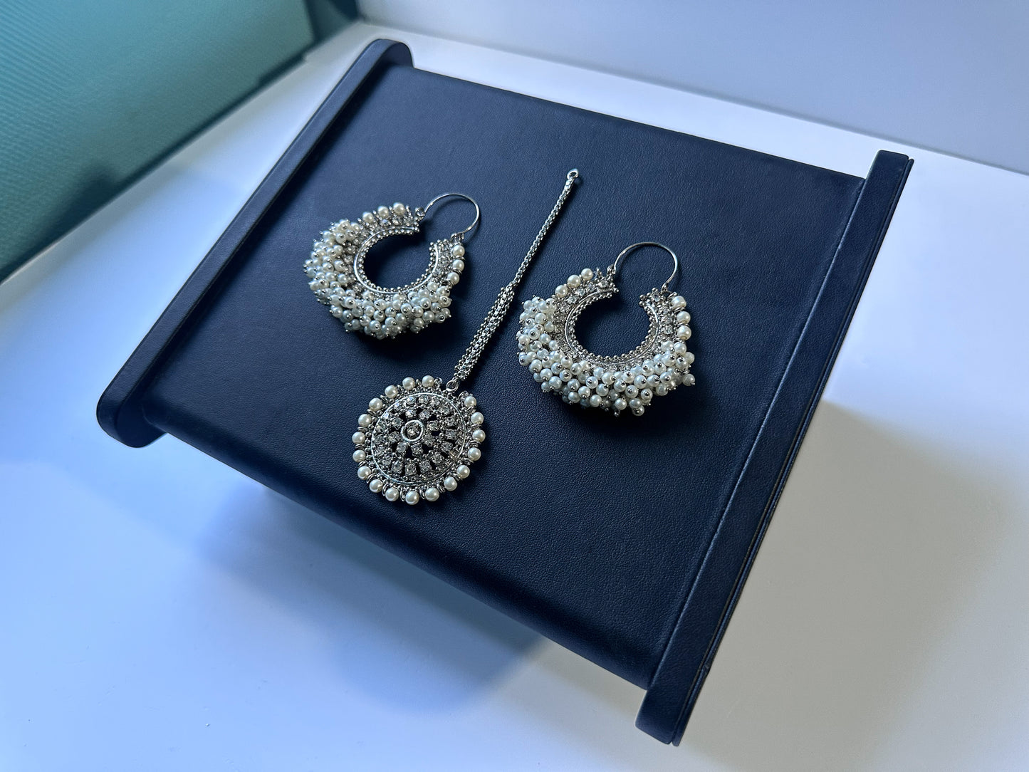 elegant silver white chand bali earrings tikka set on a black display. pakistani trending earrings tikka