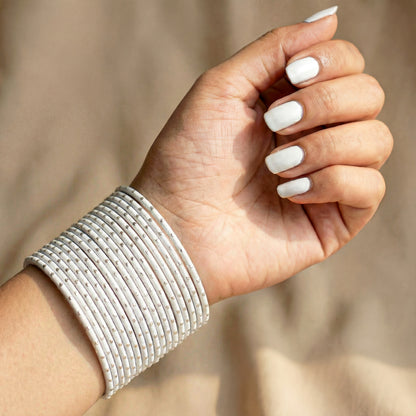 Model wearing white bangles with silver dots churi set on wrist showing elegant Indian bridal jewellery styling indian jewellery
